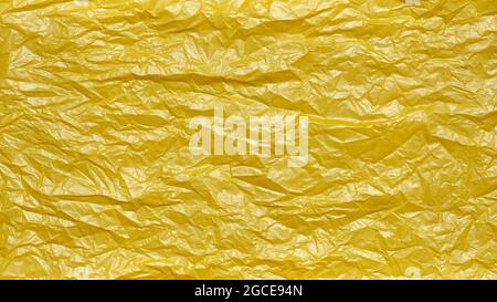 Crumpled Plastic Bag Texture, Yellow Creased Plastic Sheet, Abstract Shapes for Background. Stock Photo