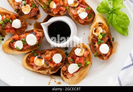 Top down view of a platter of bruschetta with a saucer of balsamic vinegar in the middle. Stock Photo
