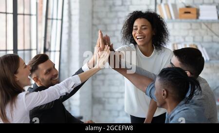 Smiling diverse employees give high five at workplace Stock Photo