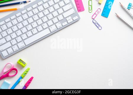 Flat lay school supplies and computer keyboard on white background. Back to school, disntance learning online concept. Top view, overhead. Stock Photo