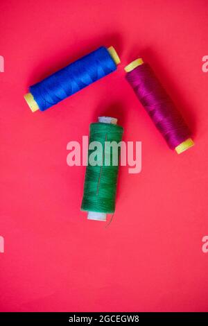 Hand sewing needle and thread close up in red background Stock Photo