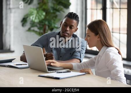 Diverse employees work together on computer at meeting Stock Photo