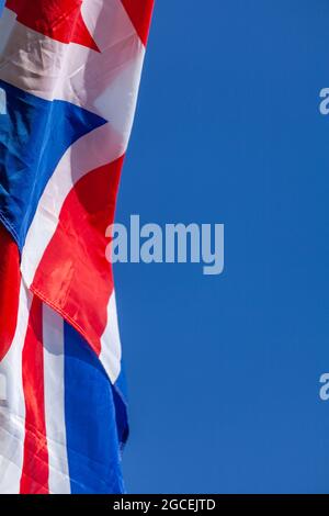 Union Jack flag flapping in the wind against a blue sky Stock Photo - Alamy