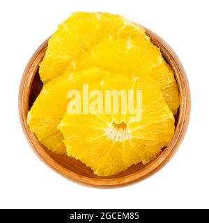 Peeled orange, cross section slices, in a wooden bowl. Sliced, fresh and ripe orange, cut sweet fruit with juicy and yellow fruit flesh. Stock Photo