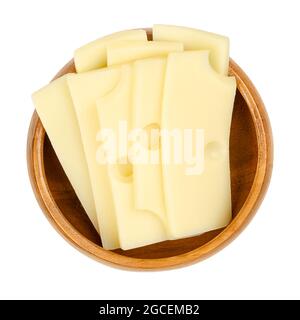 Sliced Emmental cheese, in a wooden bowl. Slices of Emmenthal or Emmentaler, a yellow Swiss cheese with holes, medium-hard. Stock Photo