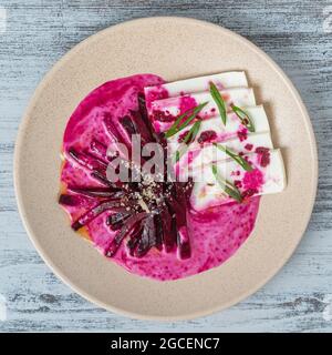 Boiled beet salad with soft feta cheese and sauce, close up, top view Stock Photo