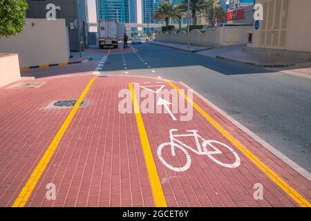 23 February 2021, Dubai, UAE: White painted bike path on the sidewalk near the highway. Concept of safe bicycle infrastructure and eco transport Stock Photo