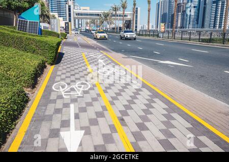 23 February 2021, Dubai, UAE: White painted bike path on the sidewalk near the highway. Concept of safe bicycle infrastructure and eco transport Stock Photo