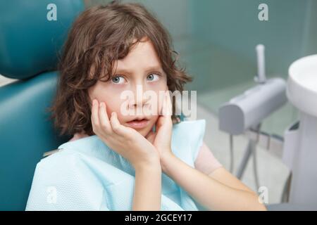 Close up of a little boy looking terrified, sitting in dental chair Stock Photo