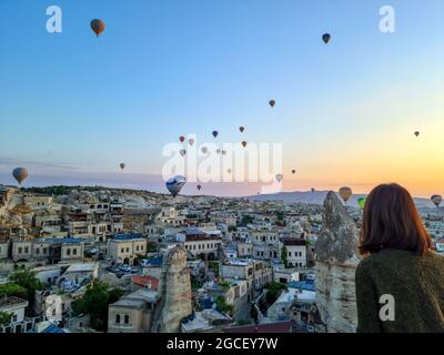 Cappadocia - Turkey, hot air balloons in the sky in the morning, tourism in Turkey. woman watching hot air balloons backwards Stock Photo