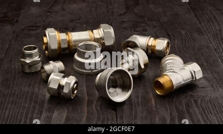 Set of brass fittings on a black wooden table. Stock Photo