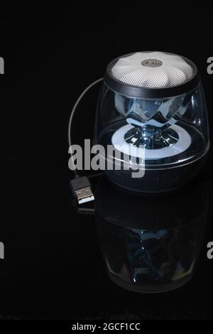 Small Bluetooth enabled audio speaker with attached USB cable used for battery charging Stock Photo