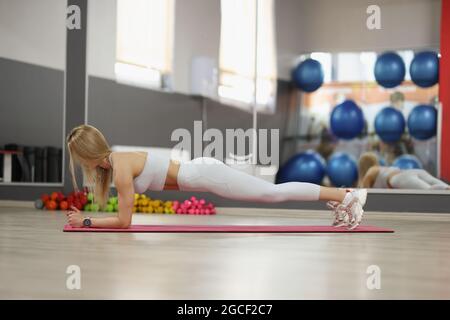 Strong beautiful girl in sportswear doing plank exercise closeup Stock Photo