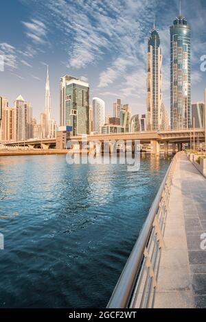 Scenic vertical panorama of high skyscrapers with offices, hotels and residential buildings in UAE. Road over the bridge and flyover passes through Du Stock Photo