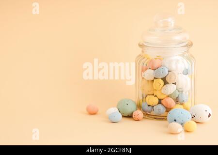 Multicolor Easter candy eggs on beige background. Stock Photo