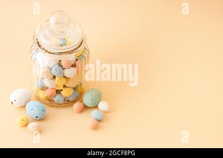 Multicolor Easter candy eggs on beige background. Stock Photo