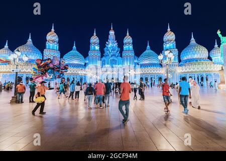 26 February 2021, UAE, Dubai: Visitors and tourists walk through the streets of the Global Village illuminated in the evening with pavilions of many c Stock Photo