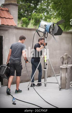 Behind the scene. Filmmaking lighting technician electric engineer adjusting and setup lights for movie film scene. Light Department. Film Crew Stock Photo