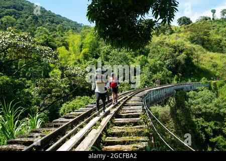 Amaga, Antioquia, Colombia - July 18 2021: Many Tourists Walking Across the Bridge of the Old Rustic Railroad in the Middle of a Forest Full of Trees Stock Photo