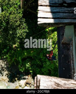 Amaga, Antioquia, Colombia - July 18 2021: Hispanic Woman Bungee Jumps in the Woods and Wait Hanging up Stock Photo