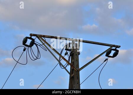 Old power pole disconnected from electricity, insulators and cables. Stock Photo