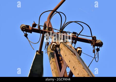Old power pole disconnected from electricity, insulators and cables. Stock Photo