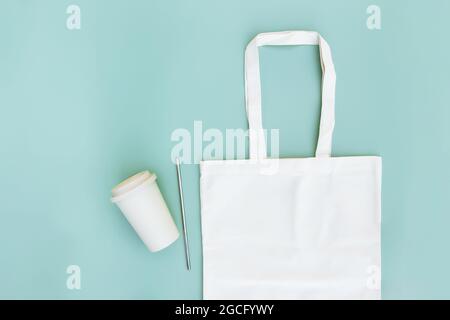 Eco white craft paper bag, metal drink straw, coffee cup on green background flat lay with copy space empty advertising area. Mock up for delivery ser Stock Photo