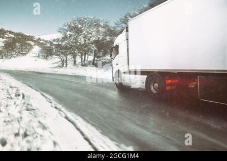 White modern truck moving fast in winter on a road with snow Stock Photo