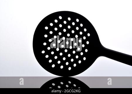 Skimmer, kitchen tools isolated on white on glossy black surface with reflection Stock Photo