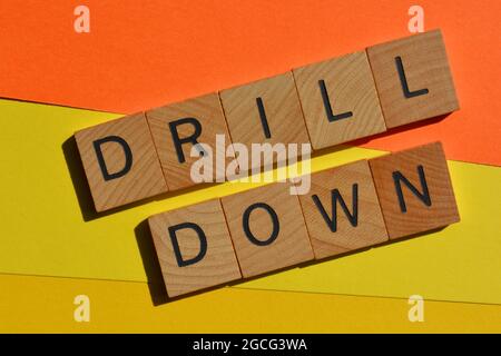 Drill Down, business buzzword in wooden alphabet letters isolated on colourful background Stock Photo