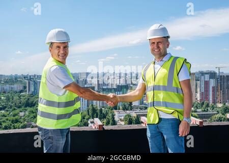 Architect and civil engineer shaking hands on the construction site. Stock Photo