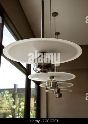 Modern style light bulb and round hanging ceiling lights decoration near glass window in cafe, vertical style. Stock Photo