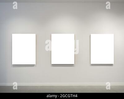 Three mockup white blank museum art frames on white clean wall background with lighting. Stock Photo