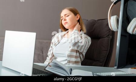 Young woman suffers from neck pain. Tired woman have headache and cervical back pain while sitting working in office or at home workspace. Long web Stock Photo