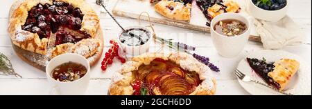 Homemade summer pies or galettes on white wooden table. Panorama, banner Stock Photo