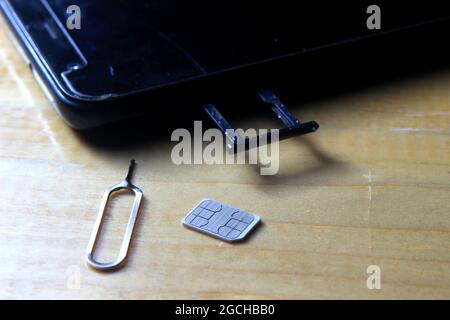 Sim CARD Ejector and Smartphone at Wooden Table Stock Photo