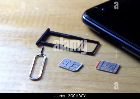 Sim CARD Ejector and Smartphone at Wooden Table Stock Photo