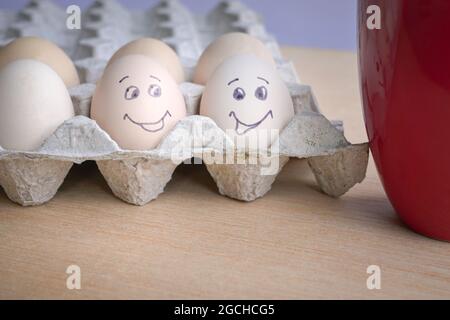 Two eggs painted with smiling face next to a red coffee cup. Good morning breakfast concept. Stock Photo