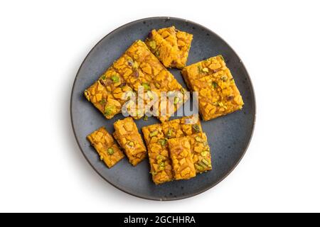 Traditional iranian dessert sohan on blue plate isolated on white background. top view, flat lay, close up. Stock Photo