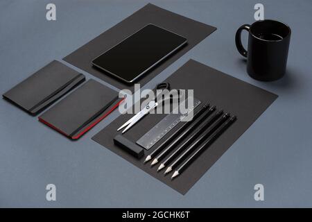 Flat lay of blank black paper sheet, black stationery items and coffee cup on gray desktop. Mock up Stock Photo