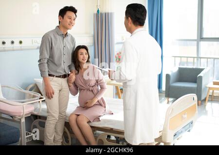 Pregnant woman talking with doctor in hospital ward Stock Photo