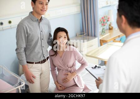Pregnant woman talking with doctor in hospital ward Stock Photo
