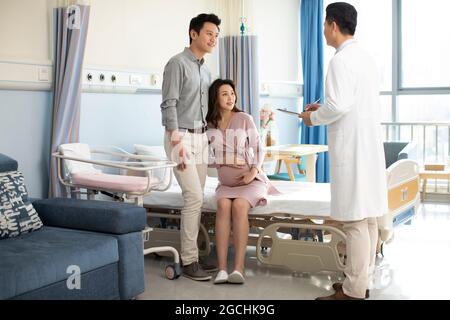 Pregnant woman talking with doctor in hospital ward Stock Photo