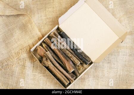 Full Cardboard Pet Treat Box on burlap fabric. Dried dog goodies. Tasty Beef Tripe Sticks. Bovine stomach. Selective focus Stock Photo