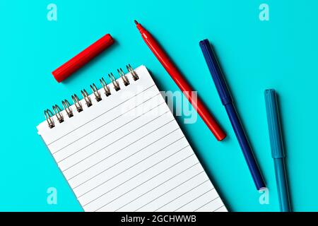 empty white notepad and multi-colored markers on turquoise background.  template for text and design Stock Photo