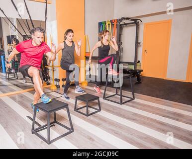 Male and female athletes doing box lunge in gym Stock Photo