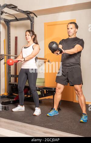 Athletic man and woman doing kettlebell swing exercise at gym Stock Photo