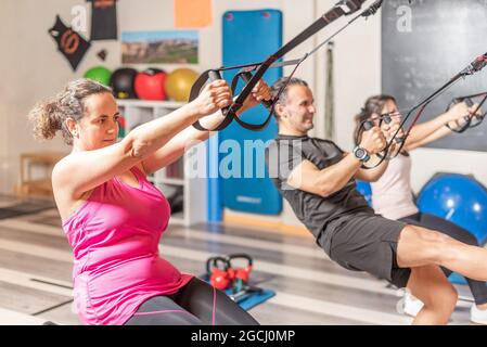 People doing exercises with fitness straps at gym Stock Photo