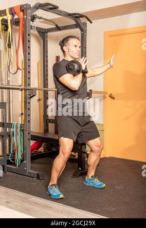 Man doing shoulder press with kettlebell in gym Stock Photo