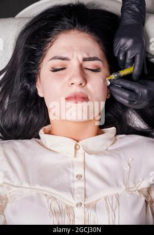 Close-up vertical snapshot of plasmolifting procedure injection. Plasma injection into skin on cheekbones of patient. Platelet-rich plasma therapy. Top view. Concept of beauty and skincare treatment. Stock Photo